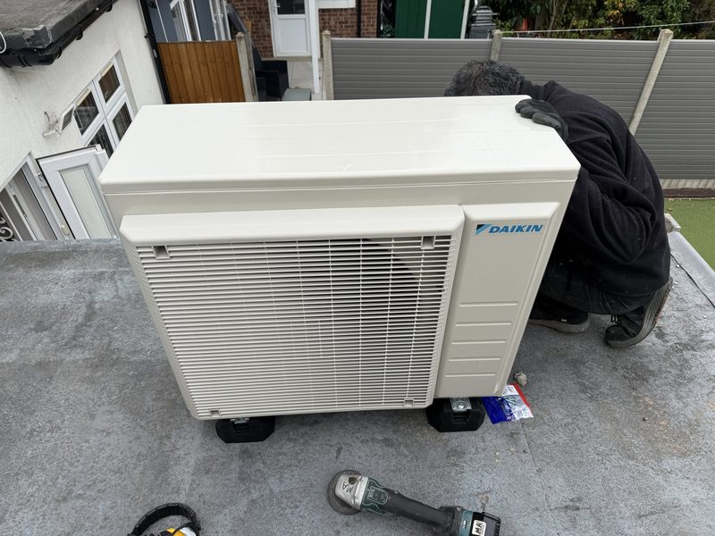 Engineer installing a Daikin outdoor unit on a flat roof